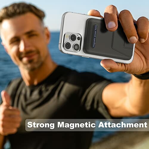 Man holding phone with magnetic attachment near water giving thumbs up